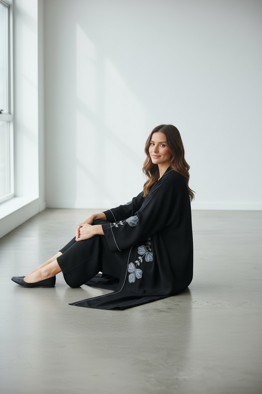 Elegant black abaya with puffy net floral appliqué and black stone embellishments seated model view