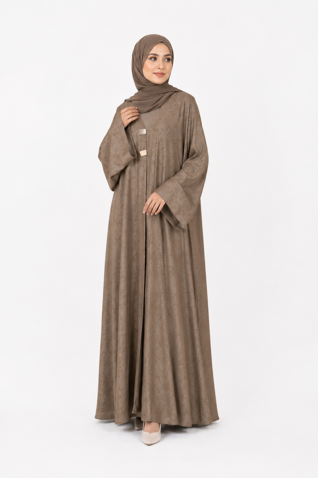 Model wearing the Floral Jacquard Open Abaya in Taupe featuring a woven floral pattern and decorative front clasp fastening by Simply Zida.